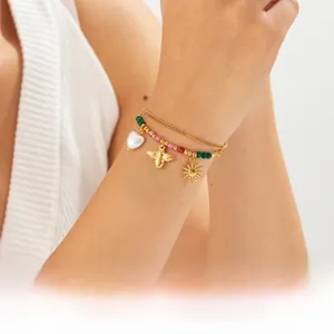 Nahaufnahme eines zweilagigen Perlenarmbands mit Herz-, Bienen- und Sonnenanhängern