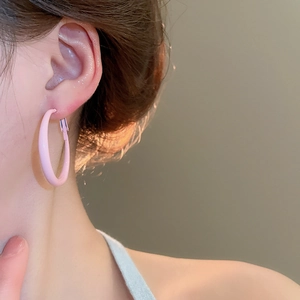 Close-up of pink round hoop earring with matte finish worn on a model ear