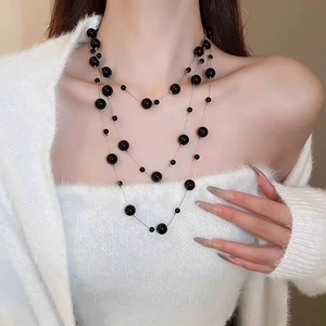 Close-up of three-layered minimalist necklace with black beads on a golden chain
