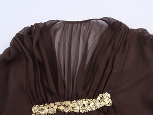 Detail of dark brown chiffon dress featuring pleats and sparkling gold sequin waistband