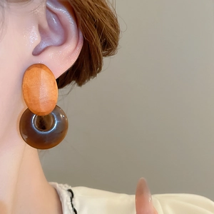 Close-up of geometric earrings featuring wooden studs and translucent resin hoops