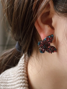 Detail of vintage butterfly stud earrings with purple zircons and blue beads on ear