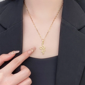 Vintage 18K gold plated snake pendant necklace with zircon crystals worn on a black suit