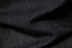 Vue macro d'un tissu en coton denim noir délavé montrant la texture sergé fine