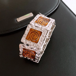Macro detail of vintage square elastic bracelet with amber resin and spiral metal texture
