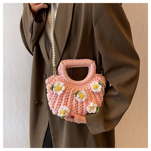 Pink hand-woven bag with 3D white daisies and a pearl chain strap shown on a model
