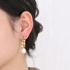 Gros plan de boucles d'oreilles perles sur modèle avec chaîne en or 18 carats et perles