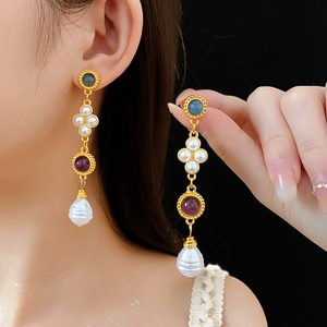 Detail of vintage gold earrings with purple stones and baroque pearls on model