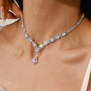 Close-up of luxury silver V-necklace with sparkling zircons and pink pear-shaped gemstone