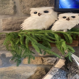 Detail of decorative white feathered owls on green pine needles for Christmas mantle