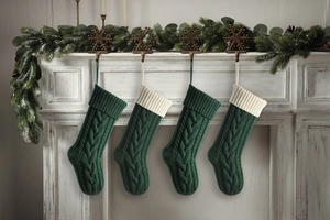 Detailed knit pattern on dark green Christmas stockings hung on a festive mantel