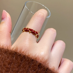 Macro detail of 24K gold plated textured red enamel ring with woven design on hand