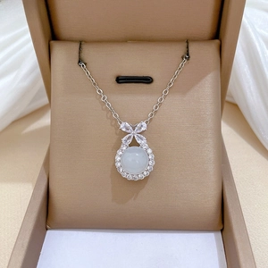 Detail of bow-knot necklace with translucent round pendant and silver-tone chain