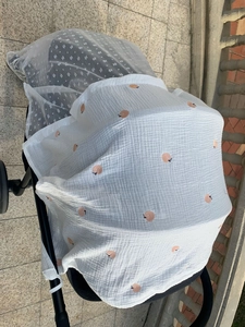Detail of baby stroller cover featuring peach print gauze and white polka dot mesh fabric