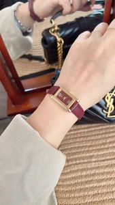 Macro shot of rectangular gold case and deep red leather strap on a woman's wrist