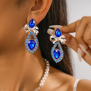 Detail of luxury royal blue teardrop earrings with a silver bow knot and sparkling crystals
