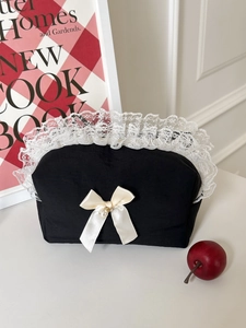 Détail de la dentelle et du nœud perlé sur un sac de rangement noir au design vintage