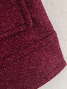 Detailansicht der burgunderroten Tweed-Textur und der präzisen Nähte der Jacke