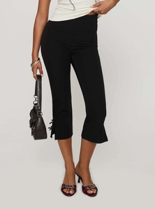 Close-up of black cropped pants featuring a stylish bow detail and side slit at the hem