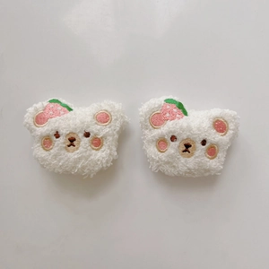 Detail showing two plush white bear accessories with cute strawberry embroidery details