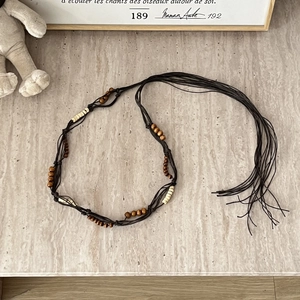 Macro detail of Bohemian braided waist chain with wooden beads and ivory accents