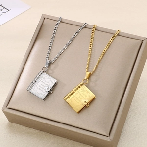 Détail de pendentifs en forme de livre or et argent avec texte gravé inspirant