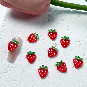 Close-up of 3D resin strawberry nail charms on a natural stone background with soft lighting