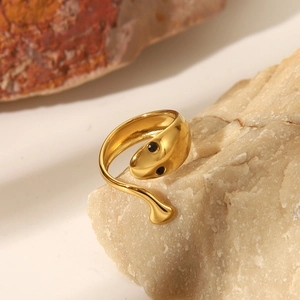Makro-Detail eines goldenen Schlangenrings mit schwarzen Akzenten auf Naturstein