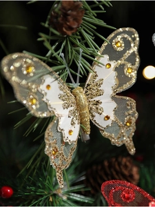 Détail de pince papillon pailletée blanche et dorée avec strass sur branche de sapin