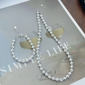 Detailed view of silver bead necklace and bracelet set with heart charms on art poster