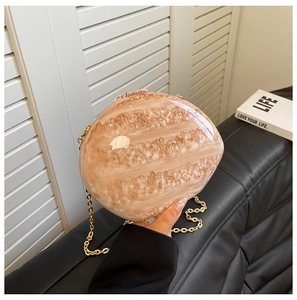 Detail of acrylic shell bag with marble texture and elegant gold chain strap