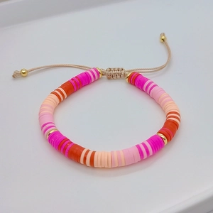 Detail of hand-woven bracelet with colorful Heishi beads and golden spacer accents