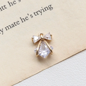 Macro detail of a gold bow pendant with square and triangle zircon stones for jewelry DIY