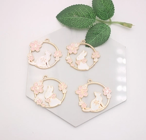 Detail of bunny and cat metal pendants with cherry blossoms on a white marble tile