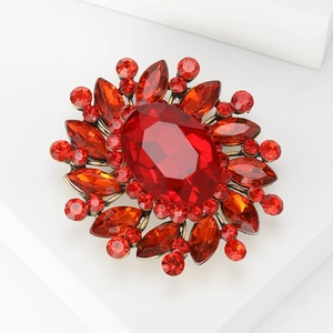 Close-up of vintage bronze flower brooch with vibrant red oval and marquise crystals