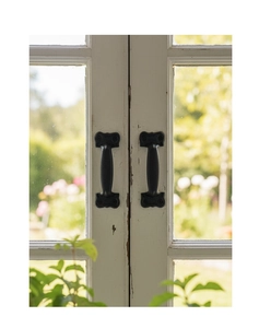 Close-up of vintage black cast iron handles mounted on white wooden window frame