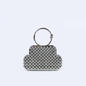 Detailed close-up of a silver beaded clutch bag with round metal handles and retro clasp