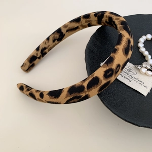 Close-up of wide leopard print fabric headband on a black plate with pearl details