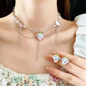 Detail von süßer rosa Erdbeer- und Herzperlenhalskette mit Blumenanhängern an einem Model