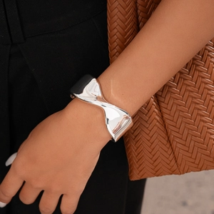 Detail shot of a silver twisted geometric cuff bracelet worn by a model in a fashion setting