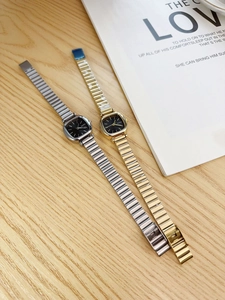 Detail shot of vintage square dial watches with elegant metal straps on a wooden table