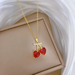 Close-up of golden cherry necklace with red heart crystals on jewelry box
