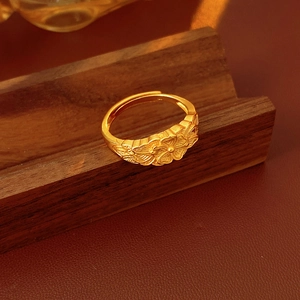 Dettaglio dell'anello vintage a croce floreale dorata con fascia regolabile su legno