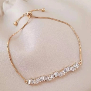 Elegant gold-tone adjustable bracelet featuring baguette-cut zircon stones with sliding clasp