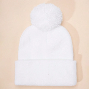 Detailed view of white knitted beanie with large fluffy pom-pom and folded cuff
