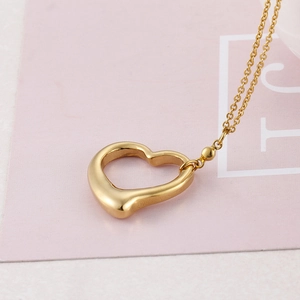 Golden heart pendant necklace with round beads displayed on a minimalist pink card