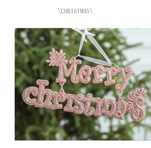 Macro shot of a pink Merry Christmas letter ornament with glitter on a festive tree