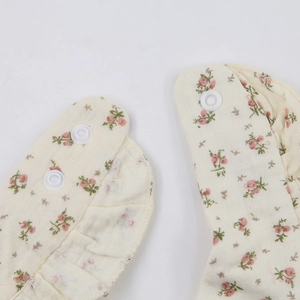 Macro shot of cotton gauze baby bib with vintage floral print and plastic snap buttons
