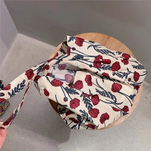 Detail of floral cotton tote bag with red poppy print on a wooden stool