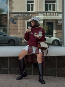 Sweat bordeaux brodé avec jupe courte et bottes hautes dans une tenue décontractée chic